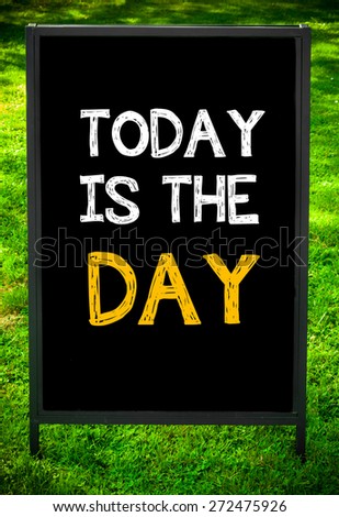 TODAY IS THE DAY  message on sidewalk blackboard sign against green grass background. Copy Space available. Concept image