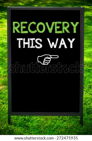 RECOVERY THIS WAY  message on sidewalk blackboard sign against green grass background. Copy Space available. Concept image