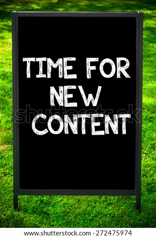TIME FOR NEW CONTENT  message on sidewalk blackboard sign against green grass background. Copy Space available. Concept image