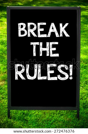BREAK THE RULES!  message on sidewalk blackboard sign against green grass background. Copy Space available. Concept image