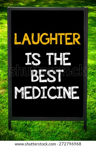LAUGHTER IS THE BEST MEDICINE  message on sidewalk blackboard sign against green grass background. Copy Space available. Concept image