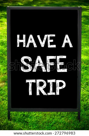 HAVE A SAFE TRIP  message on sidewalk blackboard sign against green grass background. Copy Space available. Concept image