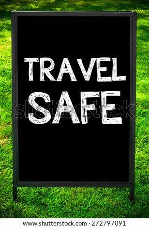 TRAVEL SAFE  message on sidewalk blackboard sign against green grass background. Copy Space available. Concept image