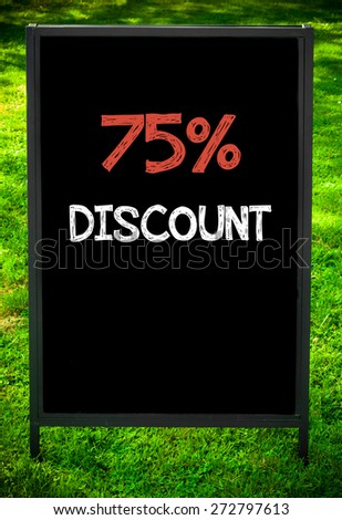 SEVENTY-FIVE PERCENT DISCOUNT  message on sidewalk blackboard sign against green grass background. Copy Space available. Concept image
