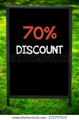 SEVENTY PERCENT DISCOUNT  message on sidewalk blackboard sign against green grass background. Copy Space available. Concept image