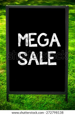 MEGA SALE  message on sidewalk blackboard sign against green grass background. Copy Space available. Concept image