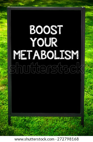 BOOST YOUR METABOLISM  message on sidewalk blackboard sign against green grass background. Copy Space available. Concept image