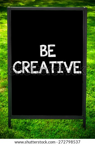 BE CREATIVE  message on sidewalk blackboard sign against green grass background. Copy Space available. Concept image