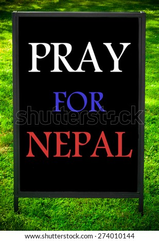 PRAY FOR NEPAL  message on sidewalk blackboard sign against green grass background. Concept image