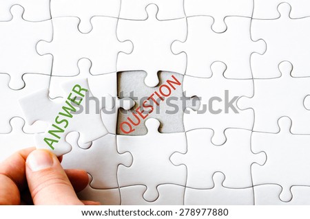 Hand with missing jigsaw puzzle piece. Word ANSWER, covering  text QUESTION. Business concept image for completing the final puzzle piece.