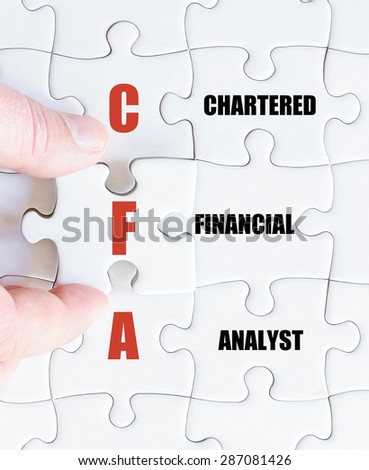 Hand of a business man completing the puzzle with the last missing piece.Concept image of Business Acronym CFA as Chartered Financial Analyst