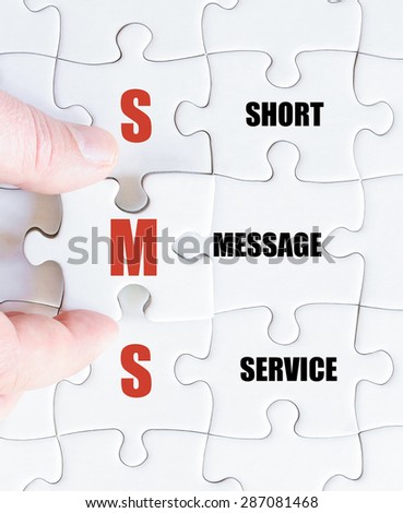 Hand of a business man completing the puzzle with the last missing piece.Concept image of Business Acronym SMS as Short Message Service