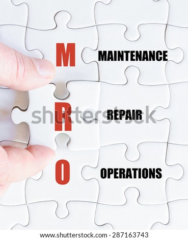 Hand of a business man completing the puzzle with the last missing piece.Concept image of Business Acronym MRO as Maintenance Repair Operations