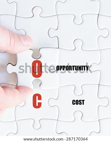Hand of a business man completing the puzzle with the last missing piece.Concept image of Business Acronym OC as Opportunity Cost