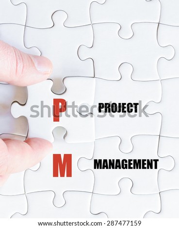 Hand of a business man completing the puzzle with the last missing piece.Concept image of Business Acronym PM as Project Management