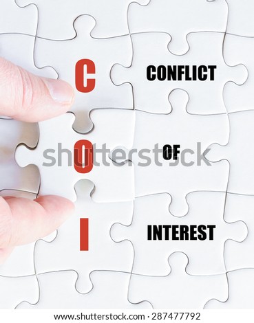 Hand of a business man completing the puzzle with the last missing piece.Concept image of Business Acronym COI as Conflict Of Interest
