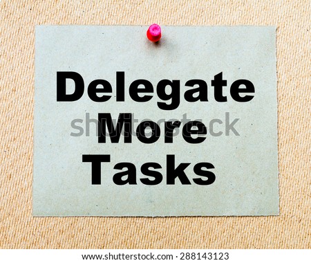 Delegate More Tasks written on paper note pinned with red thumbtack on wooden board. Business conceptual Image