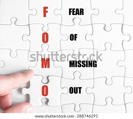 Hand of a business man completing the puzzle with the last missing piece.Concept image of Business Acronym FOMO as Fear Of Missing Out