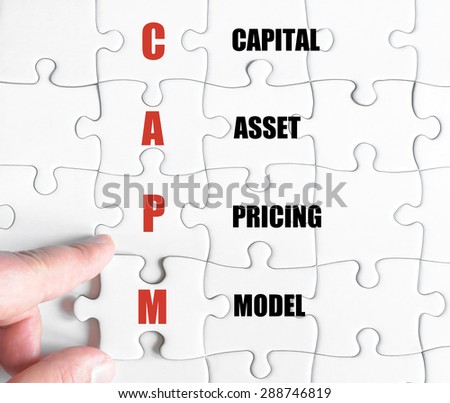 Hand of a business man completing the puzzle with the last missing piece.Concept image of Business Acronym CAPM as Capital Asset Pricing Model