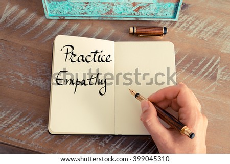 Retro effect and toned image of a woman hand writing a note with a fountain pen on a notebook. Handwritten text Practice Empathy as success and evolution concept image
