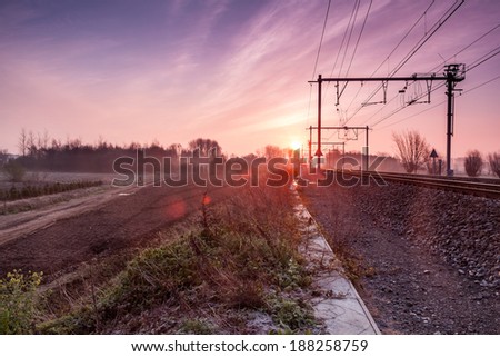 on an early morning at sunrise right next to a railway line with fog banks in the distance