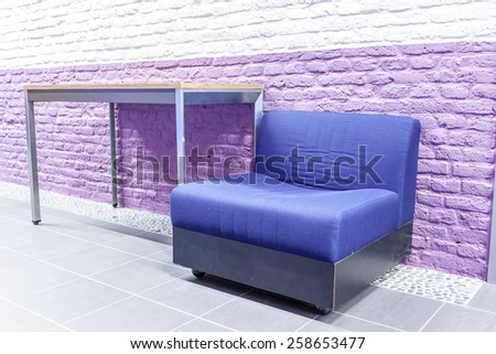 in an old building wall is painted purple with a pebble flooring and an antique chair and table