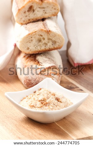 dry baguettes and bread crumbs on wooden table