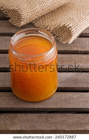 Open jar of honey on wooden background