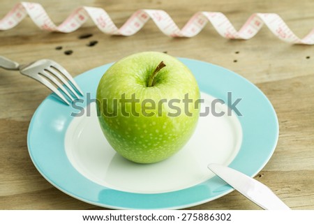 Diet concept apple with tape measure on a plate