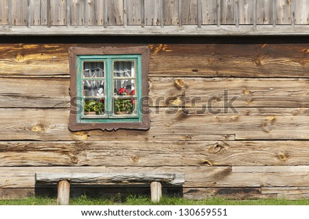 Old wooden Cottage detail with colorful window and bench in small village. Poland, Europe