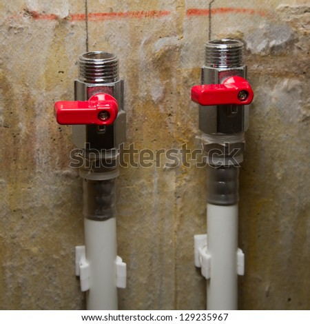 Hot and cold water valves on plastic pipes. Left valve in focus.