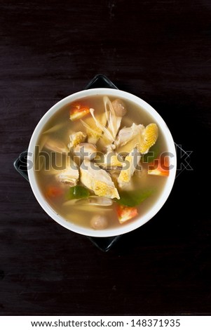 spicy chicken and herbal soup on black wooden table