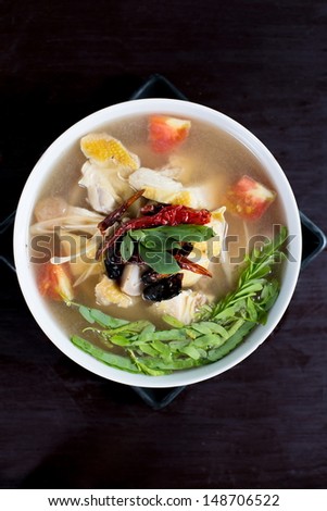 spicy chicken and herbal soup on wooden table