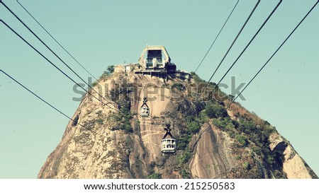 Cable car view of Sugarloaf Mountain, Rio de Janiero, Brazil. Centered point of view while using the transport, cables running out of the picture around the upper corners. Bright sunny day.
