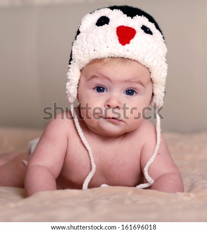 happy newborn baby in a hat with an penguin