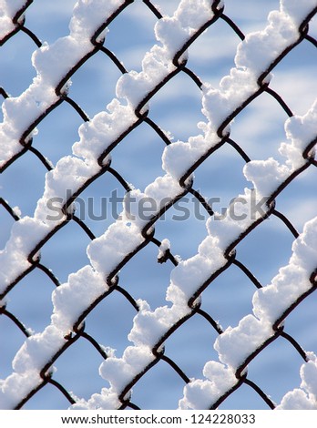 Snow piled on the wires of a chain link fence