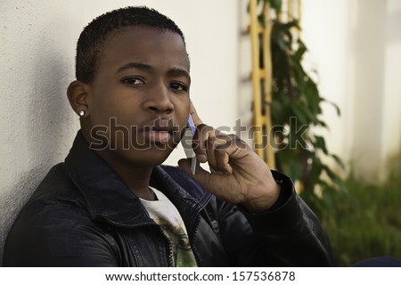 african boy on cell phone outside sitting on  grass