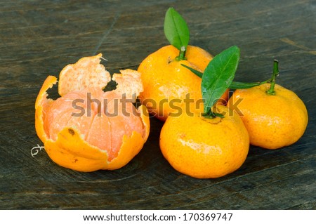 close-up of mandarins orange fruit with green leaf on wooden floor, focused on the middle of the front orange