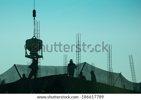 silhouette of construction workers on scaffolding working under the blue sky