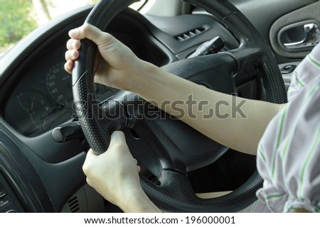 close up of woman hands driving a car (steering wheel on the left)