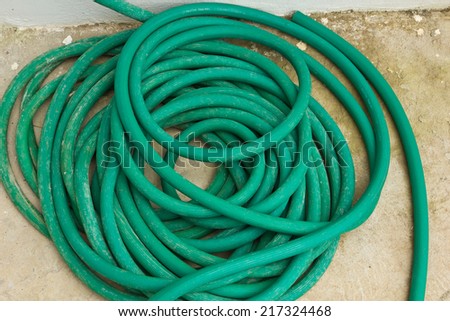 Old ever green hose on the cement floor