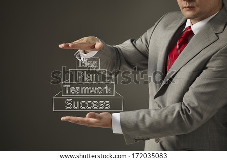 Young businessman in gray suit and red tie pointing with a marker plan, idea, teamwork, success on gray background. Studio shot.