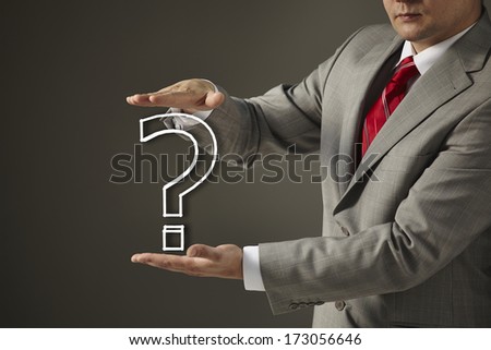 businessman in a black suit and tie holding a question mark. Concept of problem and solution