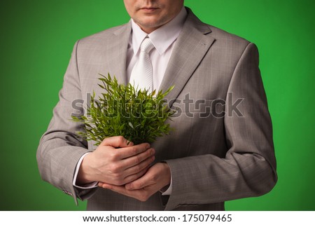 Businessman in gray suit holding small plant in his hands - grow