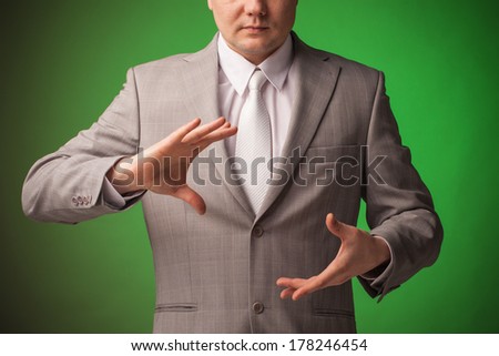 bright picture of businessman in gray suit and tie pointing one direction on green background