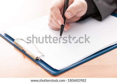 Closeup of a business man\'s hand with pen on the desk. Copy space for text.