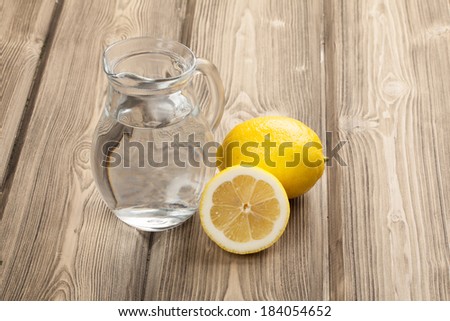 Glass with water and lemon on wooden table