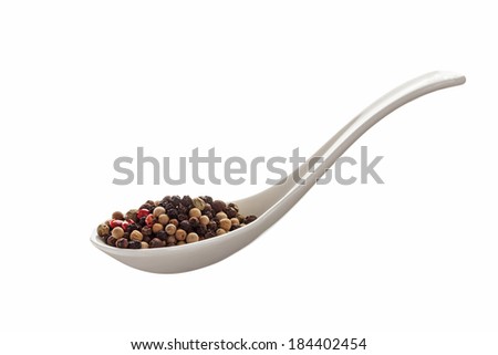 Ceramic spoons filled  whole dried black peppercorns isolated on a white background