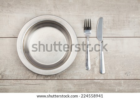 plate of metal knife fork on wood table