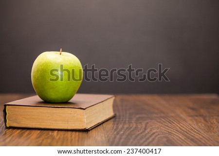 apple and book on wooden table